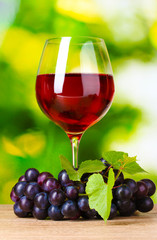 Ripe grapes and  glass of wine on  green background