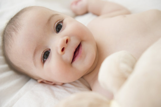 Smiling mixed race baby laying on bed