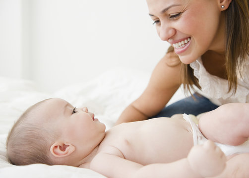 Mother smiling with baby on bed