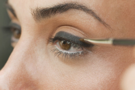 Caucasian woman putting on eyeliner