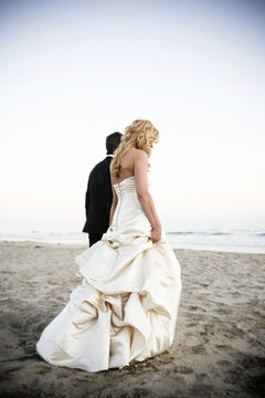 Bride and groom walking on beach