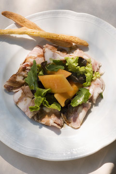 "Tuscany head cheese with salad, melon and breadsticks "