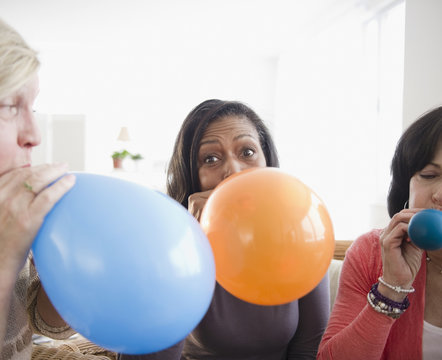 Friends blowing up balloons together - Powered by Adobe