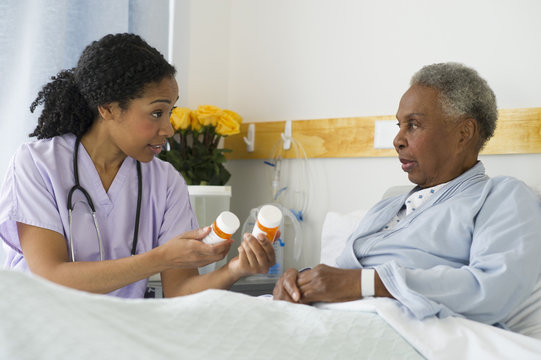 Nurse Explaining Medication To Patient In Hospital Bed