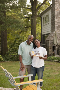 African American couple painting chair in backyard