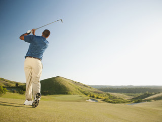 Black golfer swinging golf club