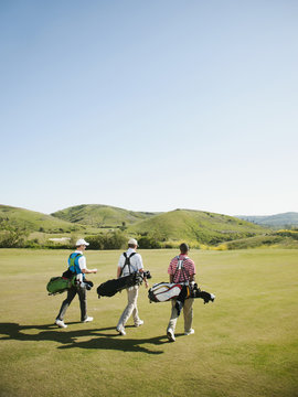 Men carrying golf bags on golf course