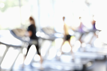 Defocused view of people on treadmills in health club