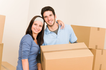 Fototapeta na wymiar Moving home young couple carrying cardboard boxes