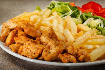 Grilled meat with French fries and vegetables