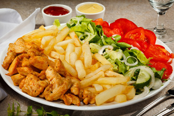 Grilled meat with French fries and vegetables