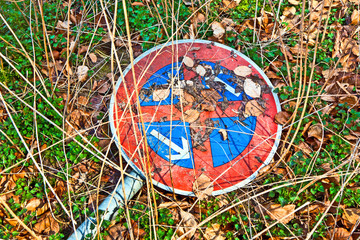 broken traffic sign no standing at any time lying in the grass
