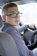 Close-up portrait of young successful man steering the car