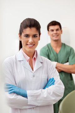 Happy female dentist smiling with arms crossed