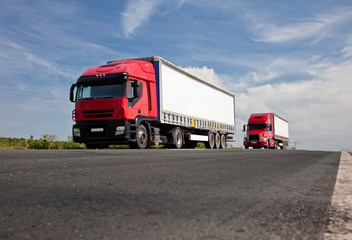 Fototapeta na wymiar Dwie czerwone ciężarówki na drodze