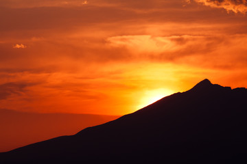 clouded orange sky with mountain silhouette