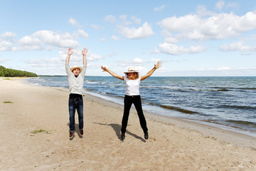 Man and woman jumping on the beach.