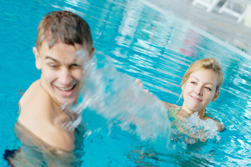Young couple splashing at the swimming pool