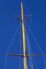 Masthead wooden mast against blue sky rigging spreaders