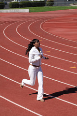 Young black woman running on track sweat suit