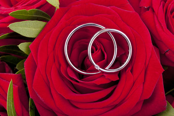 white gold wedding rings on a bridal bouquet with red roses