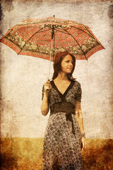 Redhead girl with umbrella at field.