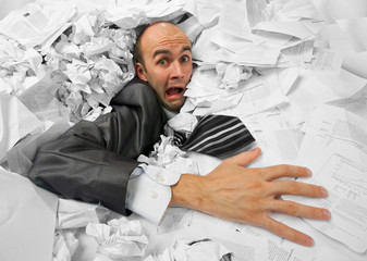 Businessman sinking in heap of documents