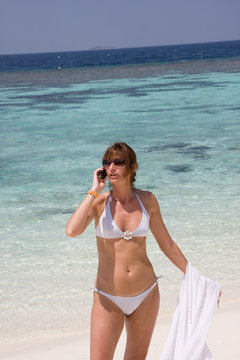 Donna in spiaggia che telefona