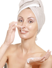The beautiful young woman in towel with a cosmetic cream..