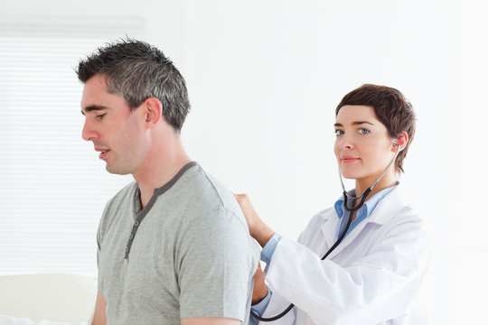 Female doctor examining a male patient looking into the camera