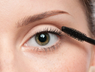 Fototapeta premium Beautiful woman applying mascara on her eyelashes