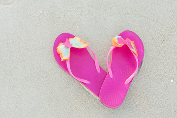 Fototapeta na wymiar A pair of pink slippers on sand beach