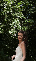 The bride in a wedding dress in park in the summer.