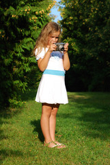 The little girl with the old camera in a white dress