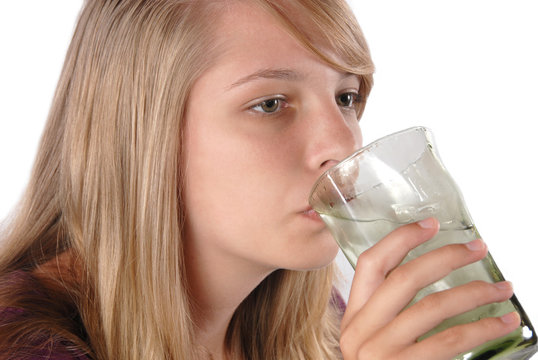 Teenage girl drinking ice water from a glass