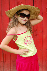 Portrait of the little girl in a hat and sun glasses