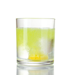 Glass with tablet in water with bubbles isolated on white