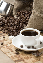 cup of coffee, beans and sack on wood