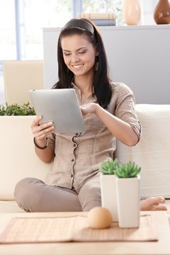 Pretty girl using tablet at home smiling