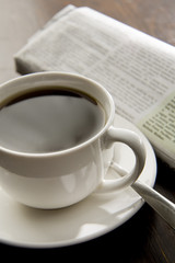 Black coffee and a newspaper in the background.