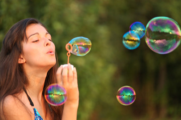 Pretty woman inflating soap-bubbles