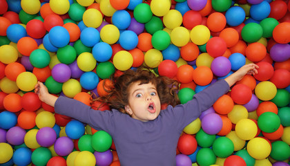 Fototapeta na wymiar colorful balls funny park little girl lying gesturing