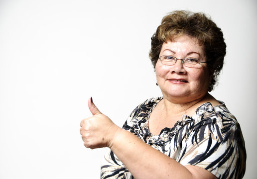 A 60 Year Old Hispanic Woman Showing The Thumbs Up Hand Sign.