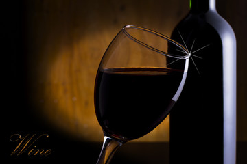 Glass and a bottle of red wine on a wooden background