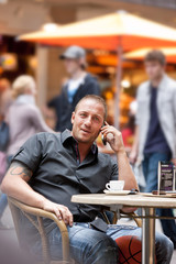 junger Mann telefoniert im Strassencafe