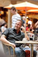 Junger Mann telefoniert im Strassencafe