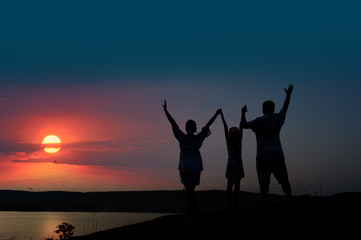 Fototapeta premium The family from three persons welcomes the sunset sun