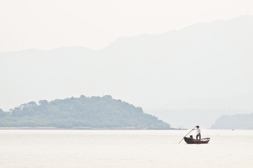 A fisherman on boat alone in the sea, low saturation picture.