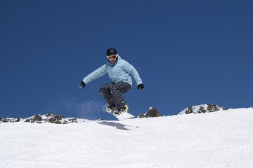 Naklejka na ściany i meble Snowboarder jumping in the mountains
