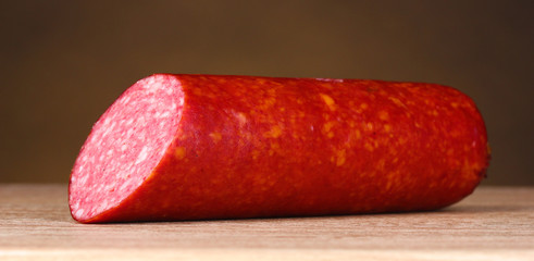 Tasty sausage on wooden table on brown background